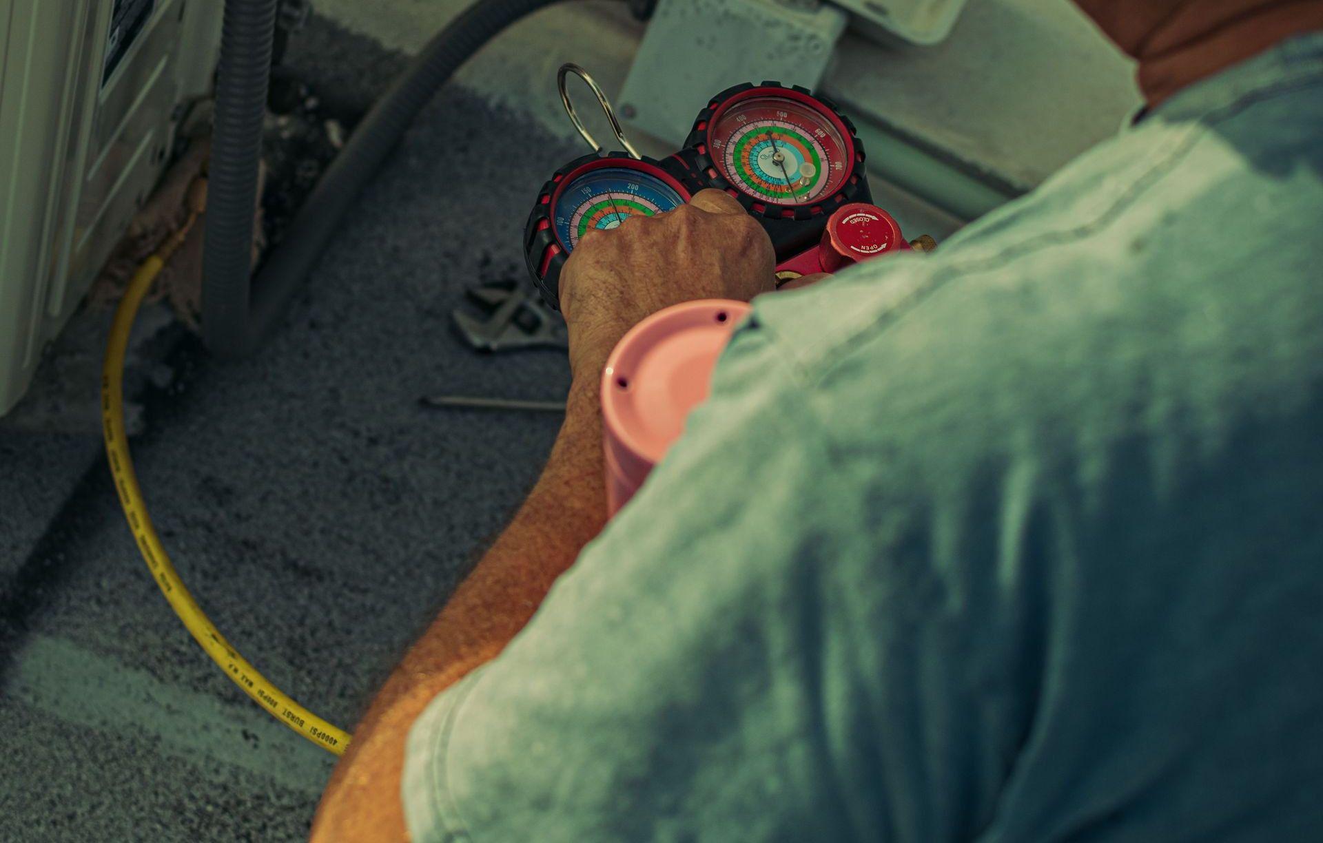 Professional technician repairing an outdoor air conditioning unit with gauges and tools.