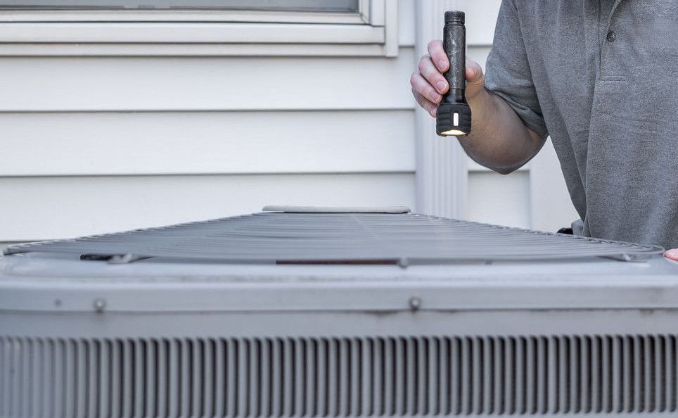 A technician inspects an outdoor HVAC unit for maintenance.